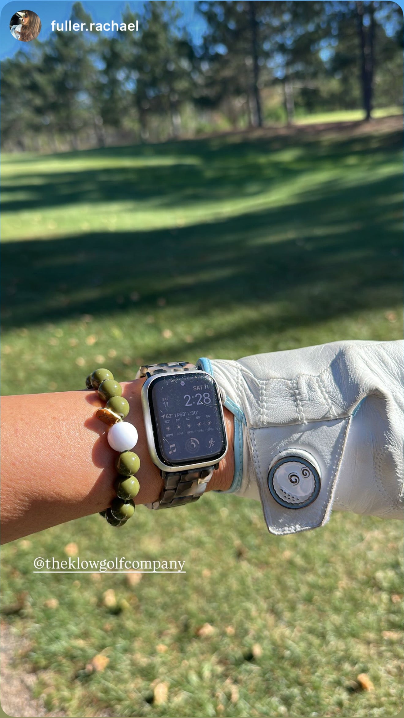 Person wearing a golf stroke counter braceletand golf glove with a golf course in the background