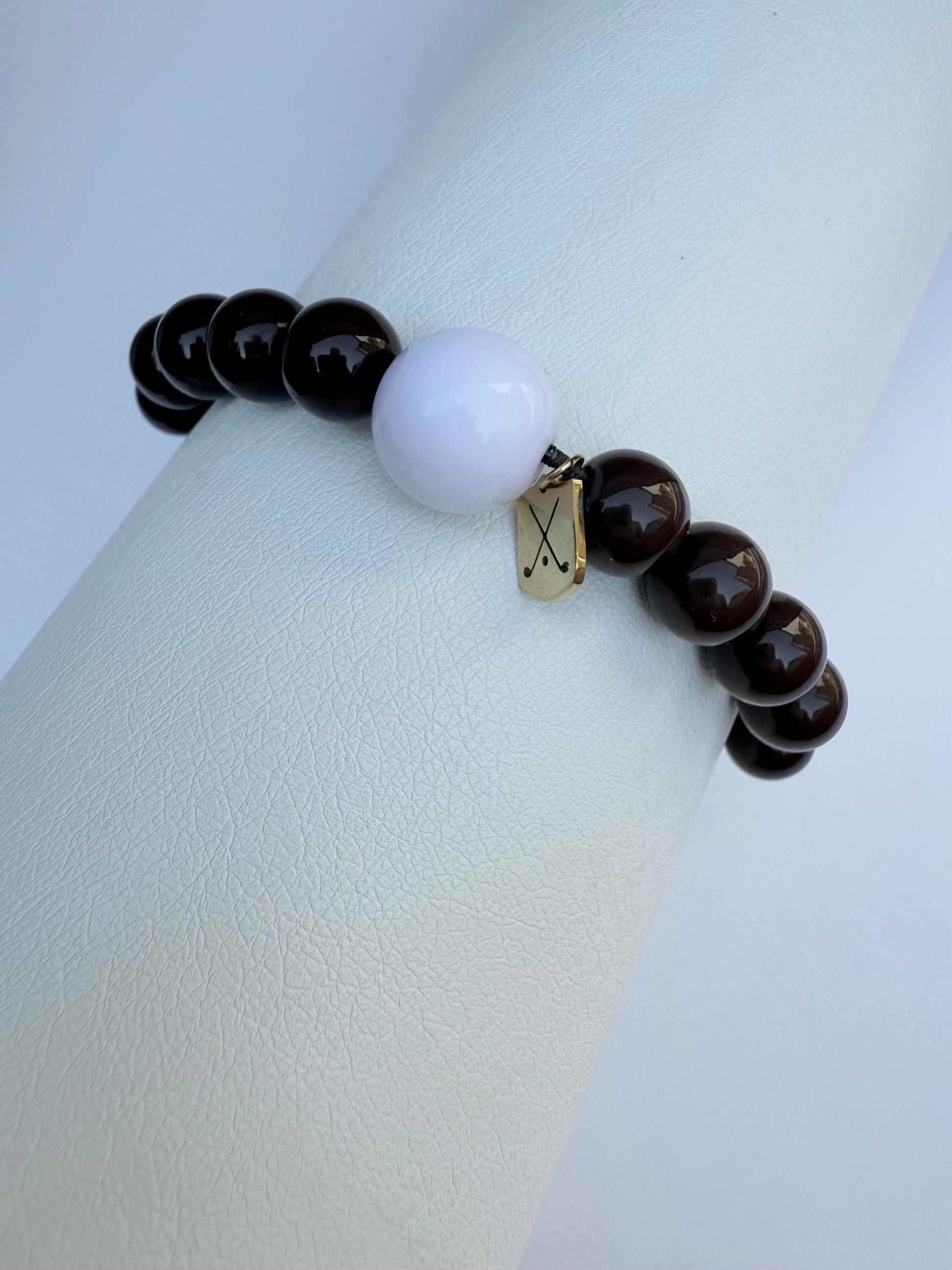 Bracelet with dark beads and a white bead on a light gray background