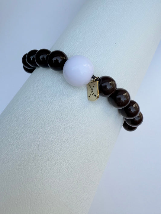 Bracelet with dark beads and a white bead on a light gray background