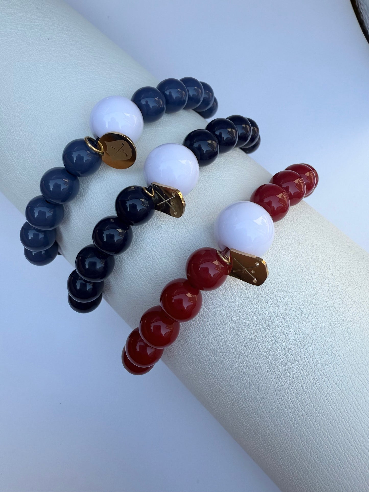 Three beaded bracelets in blue, white, and red on a white surface