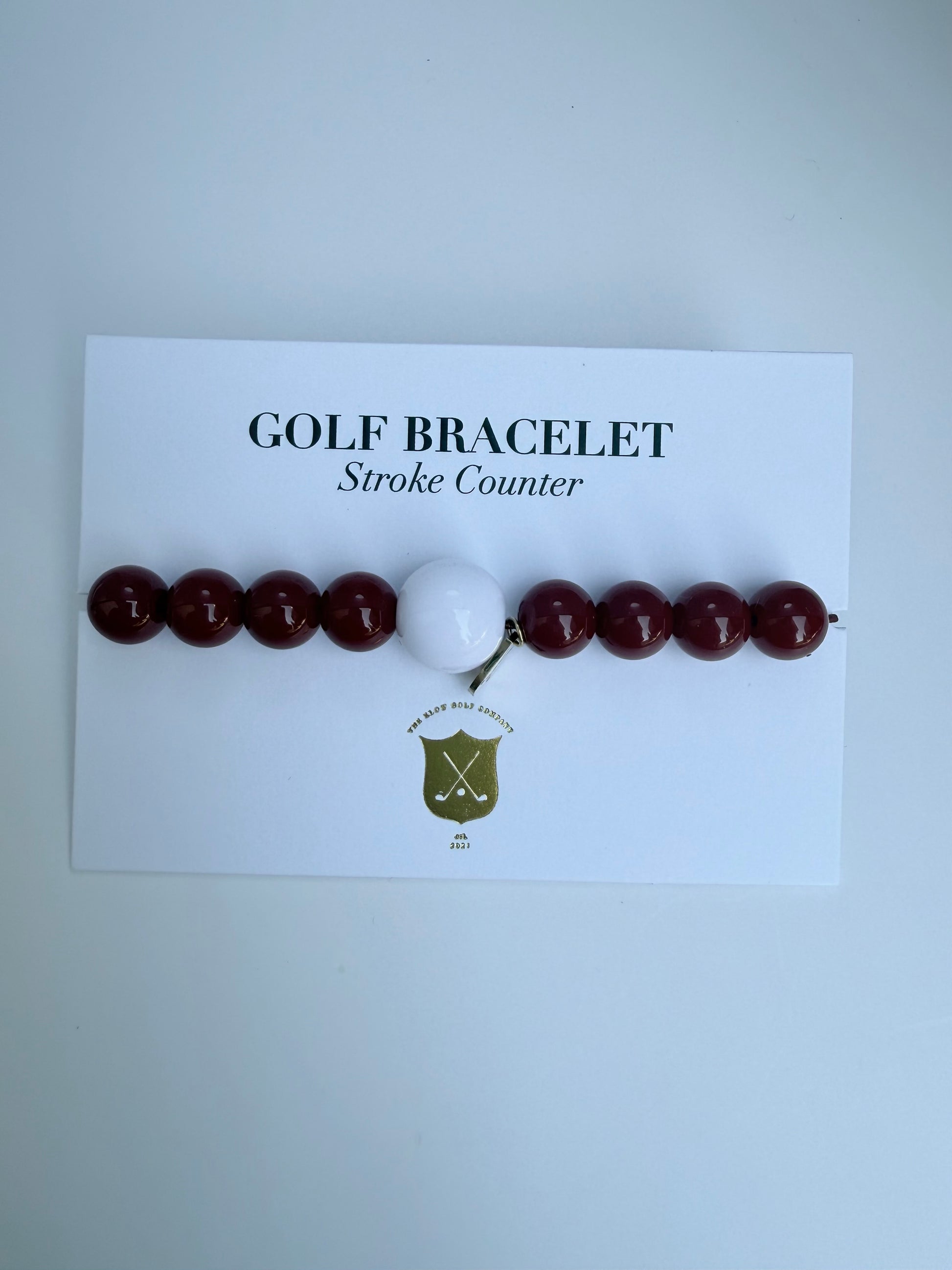 Golf bracelet with red beads and a white ball on a card labeled 'Golf Bracelet Stroke Counter' against a light gray background.