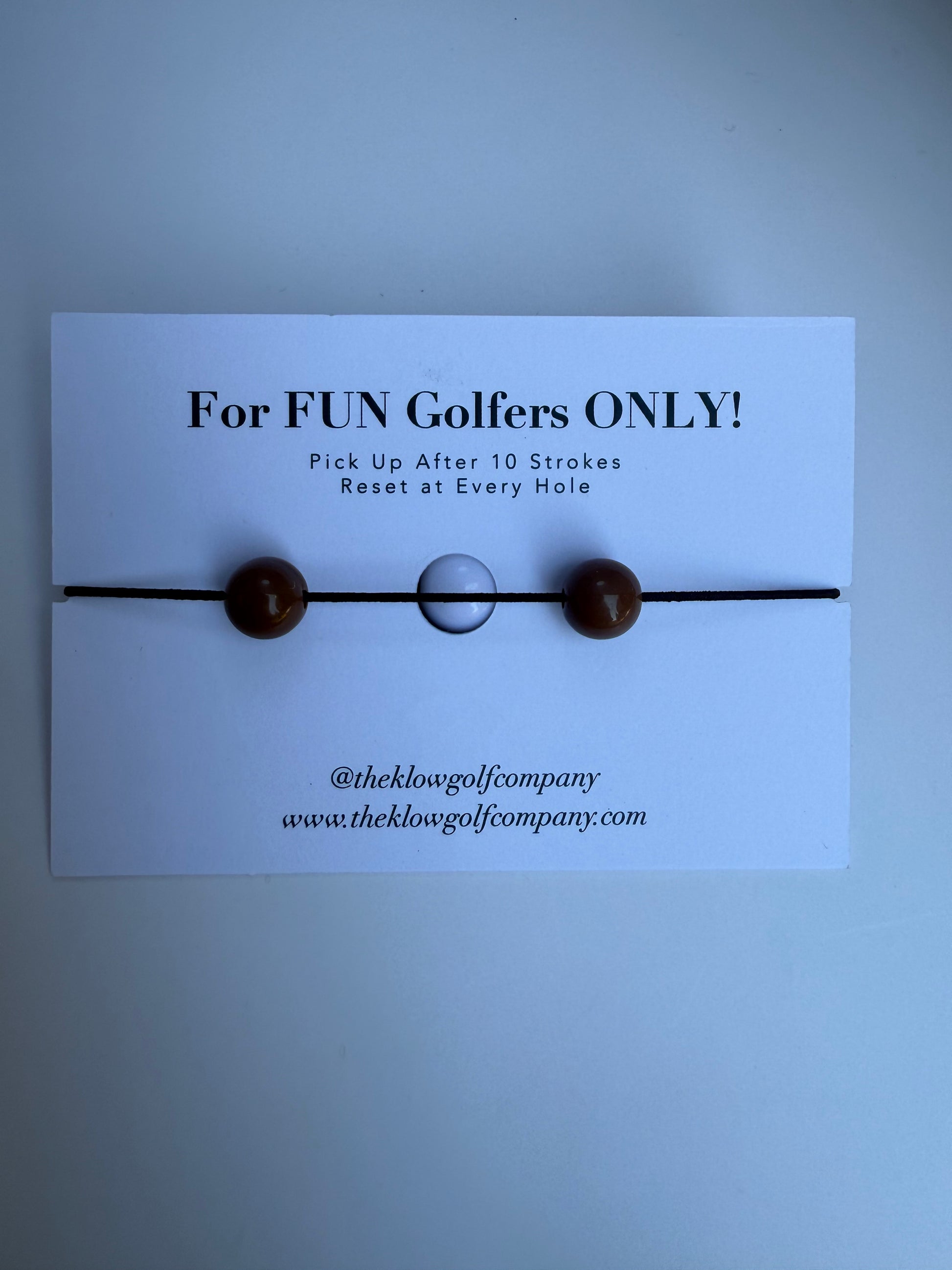 Golf ball marker with text on a white card against a light blue background
