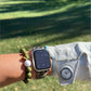 Person wearing a golf stroke counter braceletand golf glove with a golf course in the background