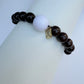 Bracelet with dark beads and a white bead on a light gray background