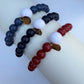 Three beaded bracelets in blue, white, and red on a white surface
