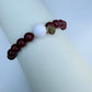 Bracelet with red beads and a white bead on a white surface
